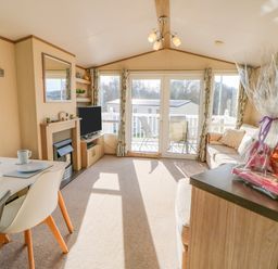 A living room with dining table chairs television fireplace and sofa with packaged gift at 46 Willowburn in Felton