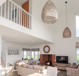 A living room with a sofa, fireplace, and television at The Beach House (Beadnell)