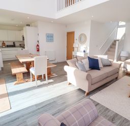 A living room with a dining table and kitchen at The Beach House in Beadnell