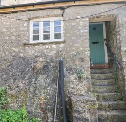 Front door with number 10 accessed by stone steps and a window on stone exterior wall at 10 Westgate Hill in Pembroke