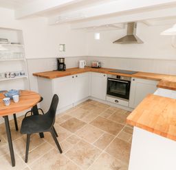A kitchen with wooden countertops a round wooden table with black chairs shelves with dishes at 10 Westgate Hill in Pembroke