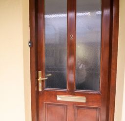 A wooden front door with frosted glass panels and a brass mail slot at 2 Garnish Court in Glengarriff County Cork