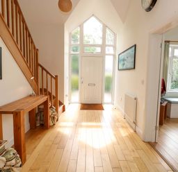 A hallway with a staircase and a console table at 1 Fernhill Avenue in Weymouth