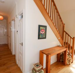 A hallway with stairs, a table, and a painting at 1 Fernhill Avenue Weymouth