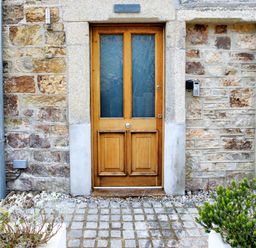 A wooden door set in a stone wall with plants on either side at The Tower 5 Corisande Manor Newquay