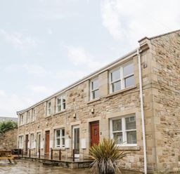 A stone building with multiple windows and doors beside a wooden picnic table at 2 Apple Tree in Beadnell