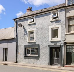 A row of connected houses with different windows and doors on a street with a sidewalk at Lane Cottage in Cardigan