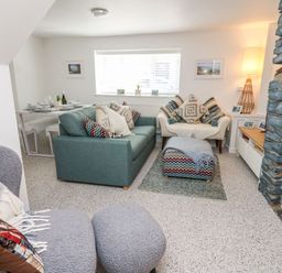 A living room with sofas cushions ottoman and a stone fireplace at Lane Cottage in Cardigan