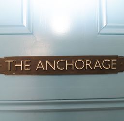 A black plaque with the text the anchorage attached to a blue door at The Anchorage in Bournemouth