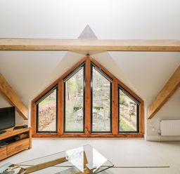 A living room with triangular windows wooden beams a television and a glass coffee table at Avon Turn View in Alderbury