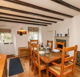 A dining room with wooden table and chairs set with plates and glasses at Riseholme in Ebberston