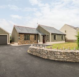 A single story house with a stone front wall driveway and garage at Timaru in Lamphey