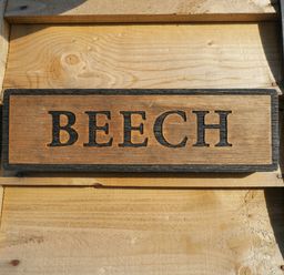 A wooden sign with the word BEECH mounted on a light wooden wall at Beech in Kemble