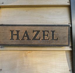 A wooden sign with the word HAZEL mounted on a light wooden wall at Hazel in Kemble