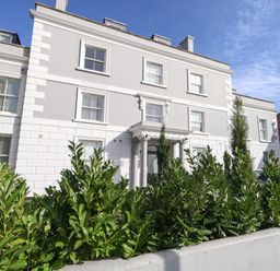A white multi-story building with columns at the entrance and green bushes in front at 3 Compass Point Weymouth