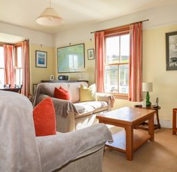 A living room with sofas cushions a wooden coffee table and framed pictures on the walls at Beachcliff in Gorran Haven