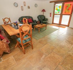 A living room with wooden dining table chairs green sofas coffee table and double doors with stained glass at Nook Bethesda near Narberth