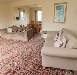 A living room with two sofas a side table a floor lamp and a dining table with chairs at Causeway Cottage in Holy Island