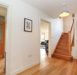 An entry hallway with wooden stairs doors and a framed picture on the wall at Whin Hill Cottage in Craster