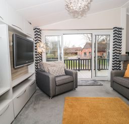 A living room with two gray sofas a wall-mounted TV and sliding glass doors at Owls Nest in Furzehill