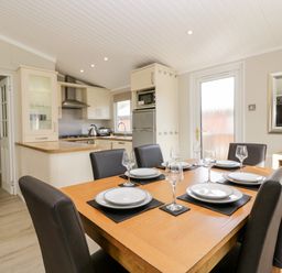 A dining table set with plates and glasses in a kitchen and dining area at Lake View Lodge in Lakeside 3 White Cross Bay Windermere