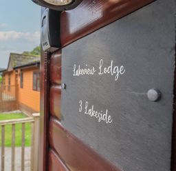 A wooden lodge with a black sign reading Lakeview Lodge 3 Lakeside at Lake View Lodge in Lakeside 3 White Cross Bay Windermere
