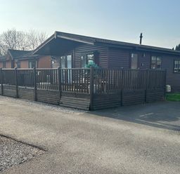 A log cabin with decking on a driveway at Lake View Lodge, Lakeside 3, White Cross Bay, Windermere