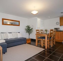 An open plan living and dining area with a sofa and dining table at The Mill in Trethevy near Tintagel