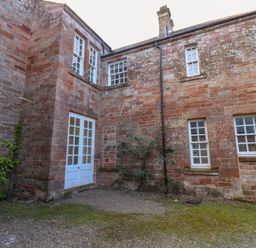 An exterior view of a brick building with white-framed windows and double doors at The Pavillion in Kirklinton near Longtown