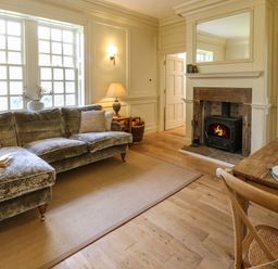 A living room with a velvet sofa a fireplace and a wooden dining table at The Pavillion in Kirklinton near Longtown