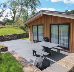 An outdoor patio area with a picnic table and benches beside a wooden building at Millstream Ridge in Haverthwaite