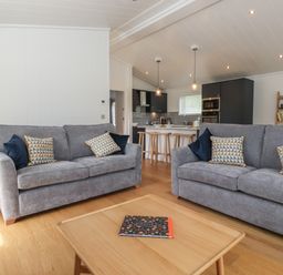 A living room with two gray sofas and a wooden coffee table in front of a kitchen area at Ash Thwaite in Haverthwaite