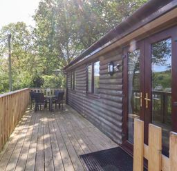 A wooden deck with outdoor table and chairs beside a log cabin at Chalet Log Cabin L2 in Combe Martin