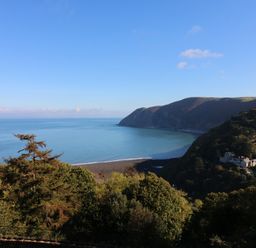 A coastal landscape with trees in the foreground hills and sea at Chalet Log Cabin L7 in Combe Martin