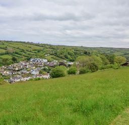 A grassy field with houses and green hills in the background at Chalet Log Cabin L12 Combe Martin
