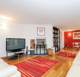 A living room with a fireplace a television and two white sofas at Great Brightor Cob Barn in St Kew Highway