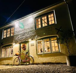 A two story building with lit windows a bicycle near the entrance and a potted plant at Old Post Office in Sherborne