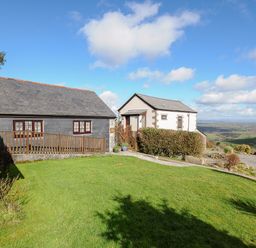 Two cottages with a grassy lawn and a distant rural landscape at Mums Cottage in Minions near Upton Cross