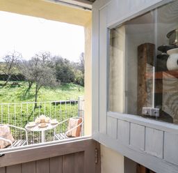 A small balcony with a table set for tea and two chairs with cushions overlooking a grassy area with trees at The Cheese Loft in White Mill near Carmarthen
