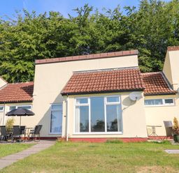 Exterior view of a bungalow with lawn and patio furniture at 39 Manorcombe Bungalows Honicombe Holiday Village near Drakewalls