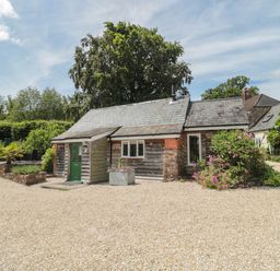 A small cottage with a green door gravel driveway and bushes at Brimley Barn in Kittisford near Milverton
