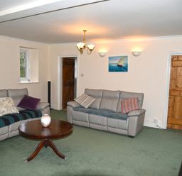 A living room with two leather sofas a round wooden coffee table and wooden doors at Heathfield in Milverton