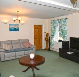A living room with leather sofas a round wooden coffee table and a large flat screen TV at Heathfield in Milverton