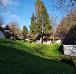 A grassy area with a small stream running through it surrounded by houses with balconies at Valley Lodge 55 in Callington near Gunnislake