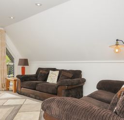 A living room with brown sofas a floor lamp and a wooden side table near a glass door at Valley Lodge 55 Callington near Gunnislake