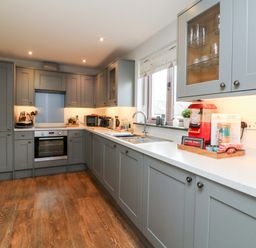 A kitchen with grey cabinets a built in oven a sink and various appliances on the counter at The Old Cowshed in Broadwoodwidger near Lifton