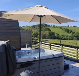 A hot tub with an umbrella on a deck at Ceunant in Llanfihangel-y-Creuddyn near Aberystwyth