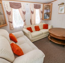A living room with two sofas with orange pillows a wooden coffee table and wall cabinets at Park Lane in Llanteg near Kilgetty