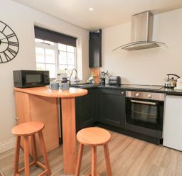 A kitchen with a bar and stools at Well Cottage Nr Malmesbury