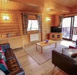 A living room with two leather sofas a coffee table a television and sliding glass doors at The Great Escape in Kenwick near Louth